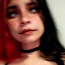 A 24-year-old woman in a selfie with dark hair and red lipstick, wearing a choker necklace and red makeup on her face.