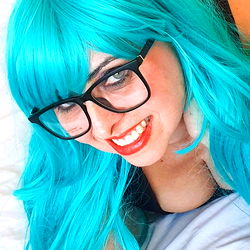Anna Rocks in a teal wig, glasses and lingerie