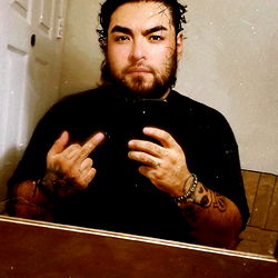 A man in a bathroom mirror flipping off the camera