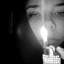 Female Individual Holding a Lit Candle in a Dark Room