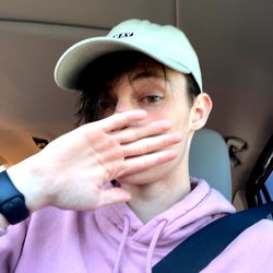 A young man on a car journey, covering his mouth