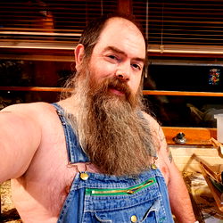 Caveman, a Bearded Man Smiling at the Camera, Stripped Shirt