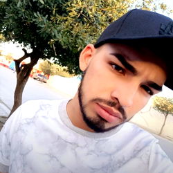 Alemán, a young man with a beard, striking a pose in a casual outfit.