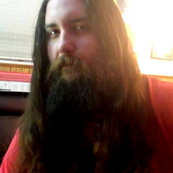 A bearded individual in a red shirt