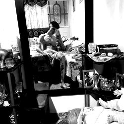 A young man in a bedroom, holding his phone and looking down