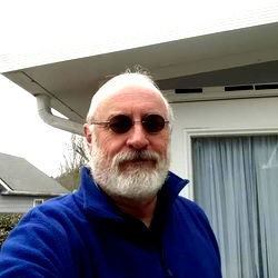 A man standing in front of a house with sunglasses on.