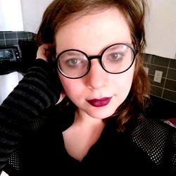 A person wearing a black shirt and glasses, with dark hair.