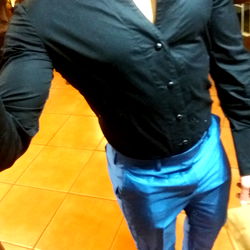 A South African model takes a mirror selfie in a formal attire, standing against a kitchen background.