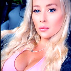Blonde beauty with pink top, in car.