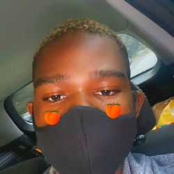 A model wearing a black face mask with the eyes showing, and a blue-green background.