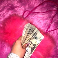 A person holding money near a pink fur item