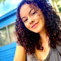 Momma, a young woman with curly hair, standing outdoors.
