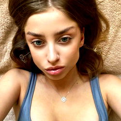 Cassy Sparks✨ in a casual pose on a beige couch.