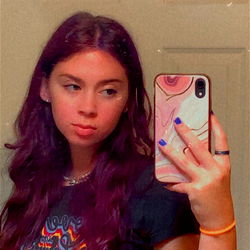 Chloe, a striking OnlyFans model with purple hair and blue eyes, showcasing her playful side on social media.