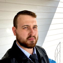 Casual pose of young man in a leather jacket against a house background