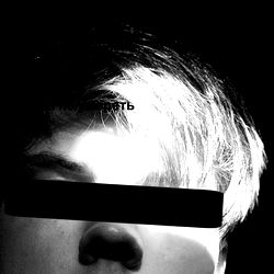 Aaron E., a model from the USA, captured in this striking black and white photograph. He is shown with a face mask, adding an element of intrigue to the image.