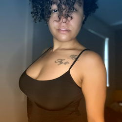 Adalia, a model showcasing her figure and style in a black tank top.