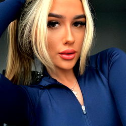 Chlo, the UK-based OnlyFans model, strikes a bold pose in her blue athletic wear. Her striking eyes and confident stance make for an intriguing image.