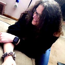 A Woman in a Bracelet and Glasses Sitting on the Floor