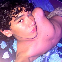 Young Adult Male with Curly Hair in Casual Attire Posing for Selfie