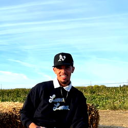 A person posing with hay bales outdoors