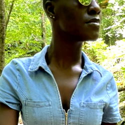 Stylish DarkRose model in a denim shirt and sunglasses, posing in a natural setting.