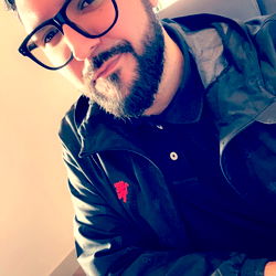 Stylish Man in Glasses and Black Jacket, Seated at Table