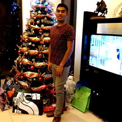 A young man posing with a Christmas tree