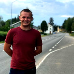 Man in red shirt standing on rural road