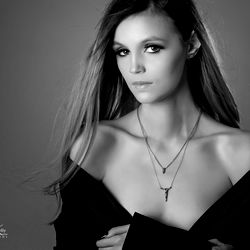 Stylized Portrait of Mae Kolberg in a Necklace, with Focus on Her Gaze and Serious Expression