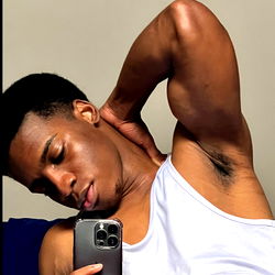 Muscular Man in a White Tank Top, Leaning Against Wall