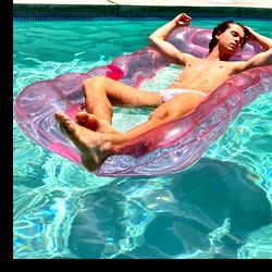 Achille Monet lounging in a ring donut pool float