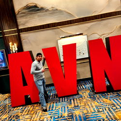 Man Standing Next to Large Awn Red Letters