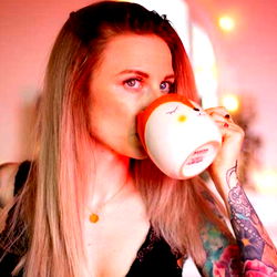 Model Angelique Grimm with tattooed arms sipping a hot beverage
