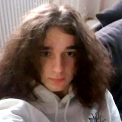 Young Adult Male with Long Hair and a White Jacket Posing for Selfie