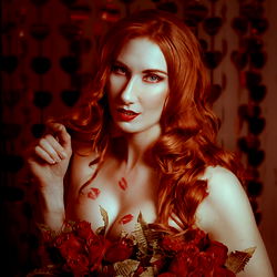 Red-haired woman in a red rose field, modeling