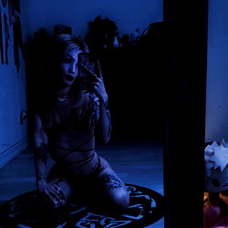 BabyDeath, a California-based OnlyFans model, strikes an alluring pose in a dark room.