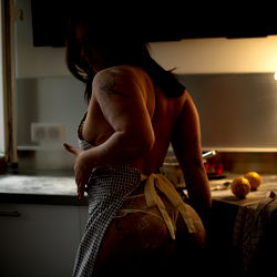 A tantalizing scene of a woman in a kitchen, captured in the act of reaching for an item.