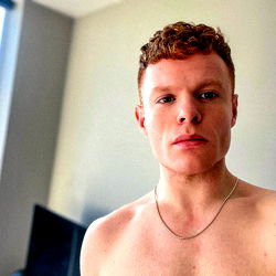 Young Man With Curly Hair, Necklace and Tattoo in Bathroom Mirror