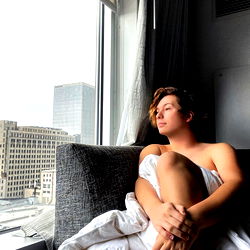 A Young Man Relaxing in His Hotel Room with City View