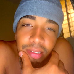 A young man in a beanie, posing with his hand on his chin.