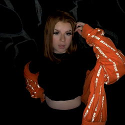 Model in a Black Shirt and Orange Jacket, Holding Her Hair