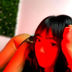 Emma, a model on OnlyFans, in a vivid red room with her hand near her face
