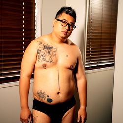 Tattooed Man in Only Briefs Standing in Room