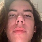 Al Smith, a young adult male with long hair and beard, showcasing his hairstyle in front of a mirror.