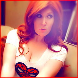 Red-haired woman wearing a Spider-Man t-shirt and a choker, with a heart emoji on her shirt