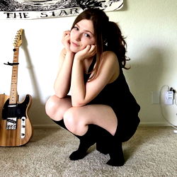 AshleeJune, a guitar-strumming artist in her studio