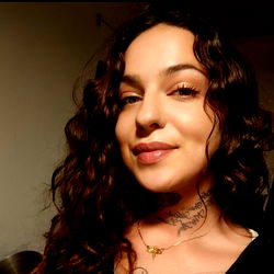 Annabella - A captivating woman with tattoos and curly hair in Switzerland