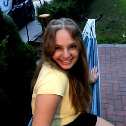 Daisy Drew, a young woman exuding joy and casual charm on her porch swing