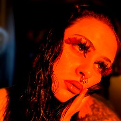 Intense and dramatic portrait of a person with striking features and makeup, evoking a sense of mystery.